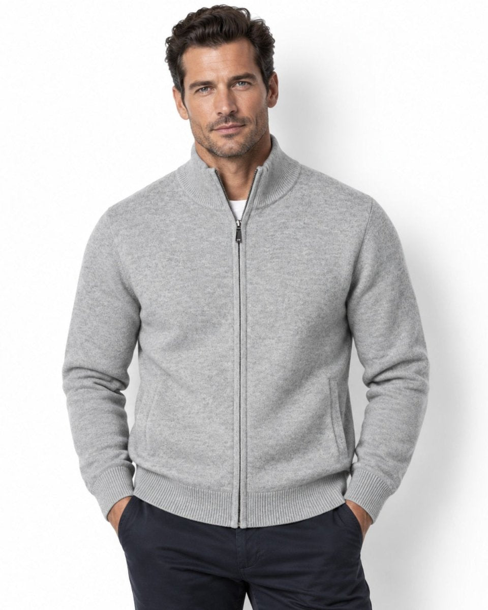 Handsome man wearing a light grey premium luxury full-zip mock neck cardigan sweater by Kouvr over a white t-shirt, standing with hands in pockets.
