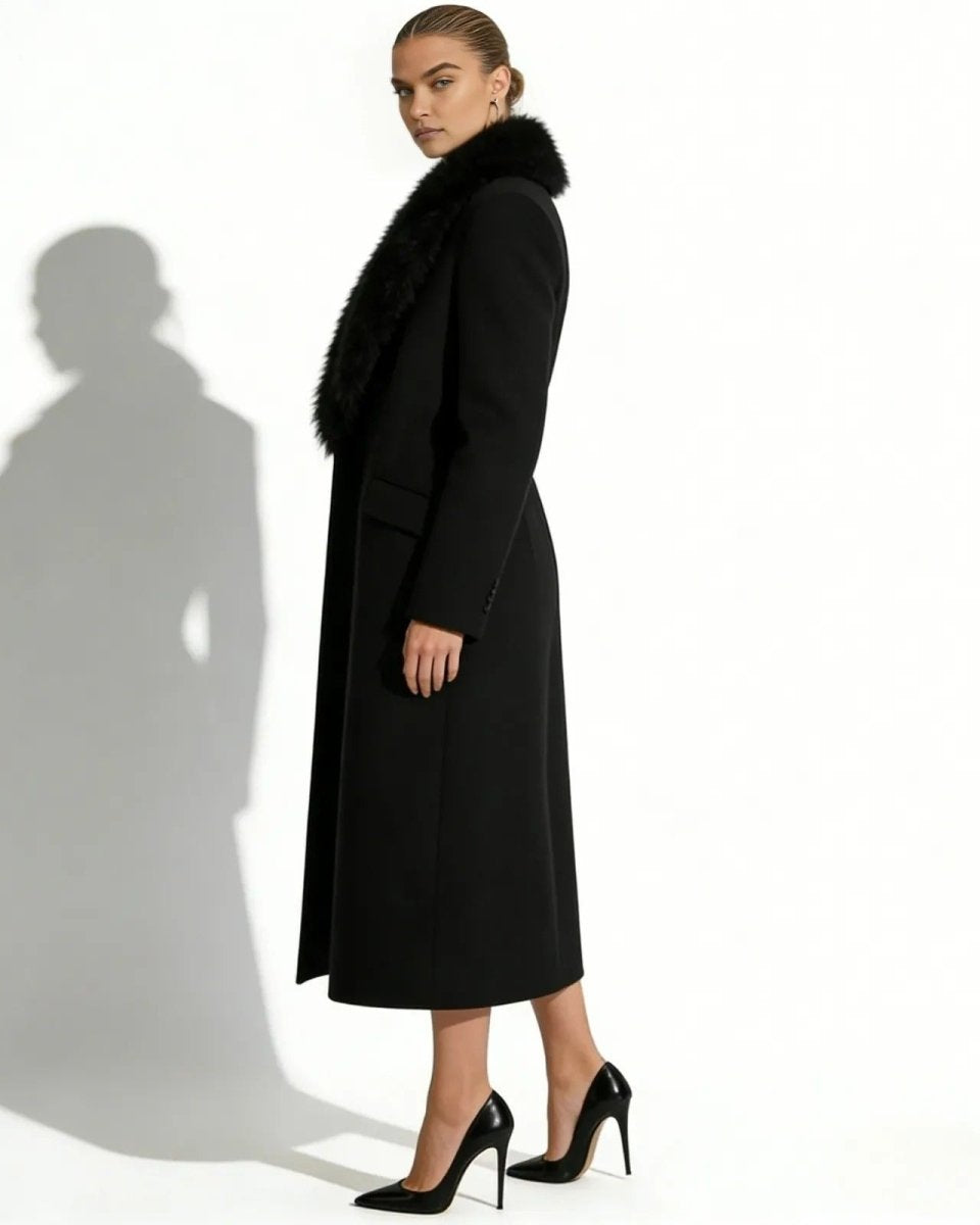 Model from the side wearing the long black single-breasted wool coat with a plush black faux fur collar and black stiletto heels.