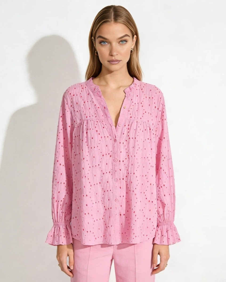 Model wearing the Lydia long sleeve pink eyelet blouse with matching pink trousers, showing the V-neck and button front.