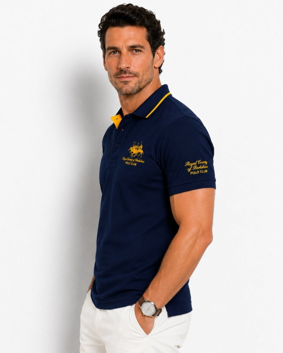 Man wearing a navy blue polo shirt with yellow accents on a white background