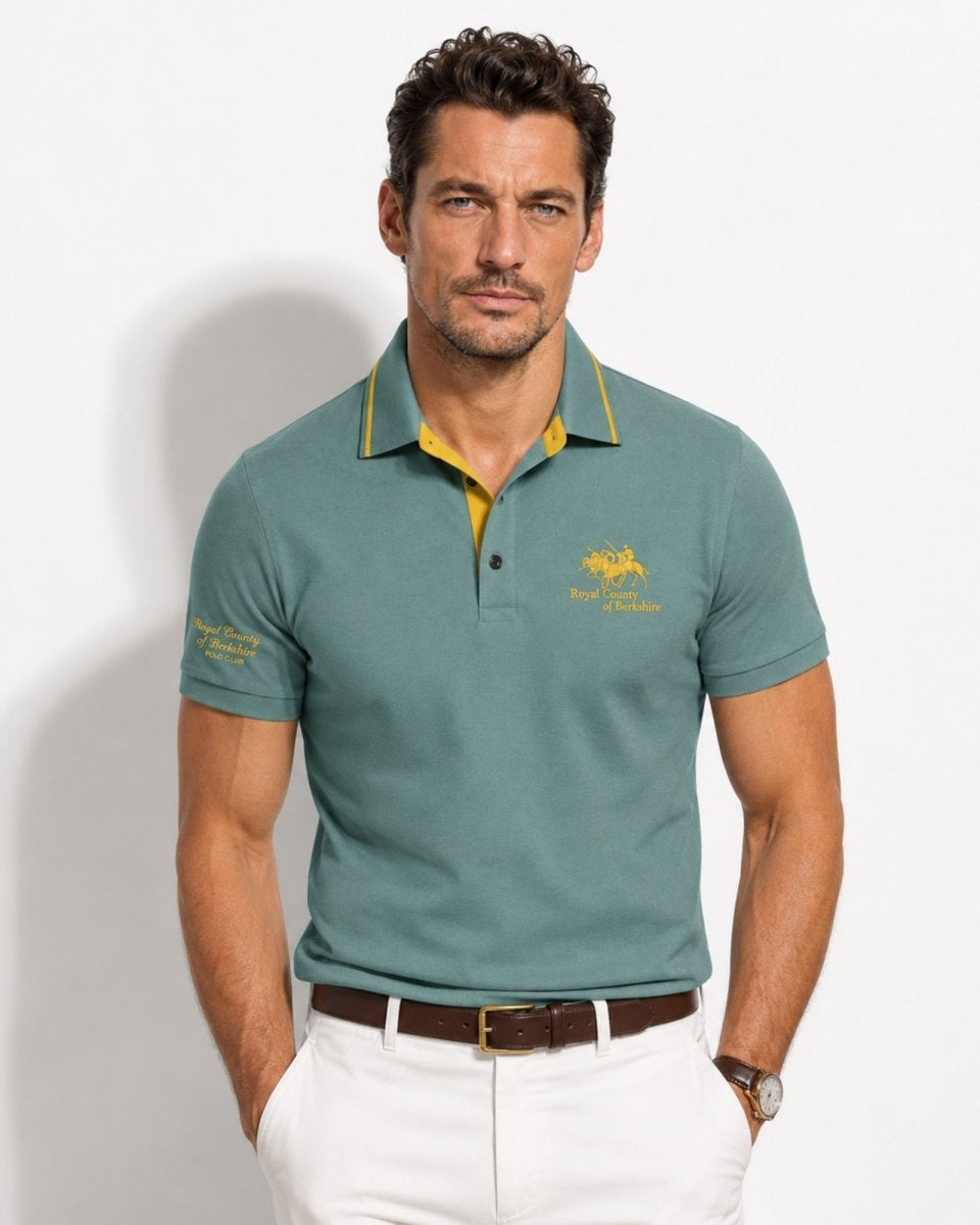 Man wearing a green polo shirt with a logo on a white background