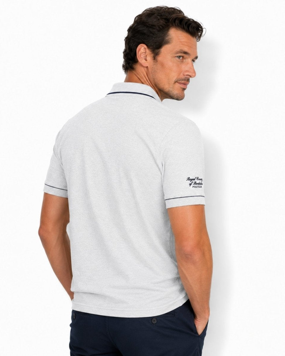 Man wearing a light gray polo shirt with a brand logo on the back, standing against a white background.