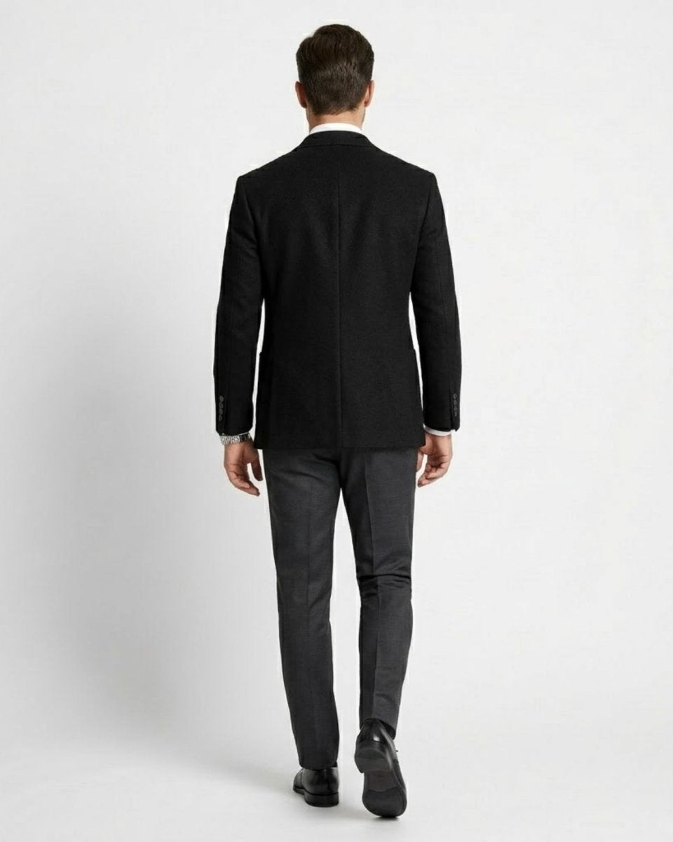 Full body back view of black wool blend blazer and dark grey dress pants in motion.