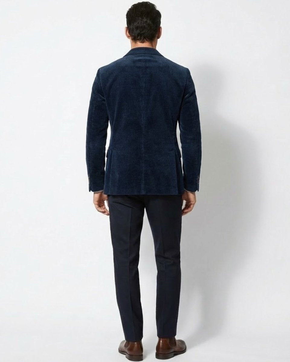 Rear view of the men's dark blue corduroy blazer highlighting its tailored construction and fit on a male model.