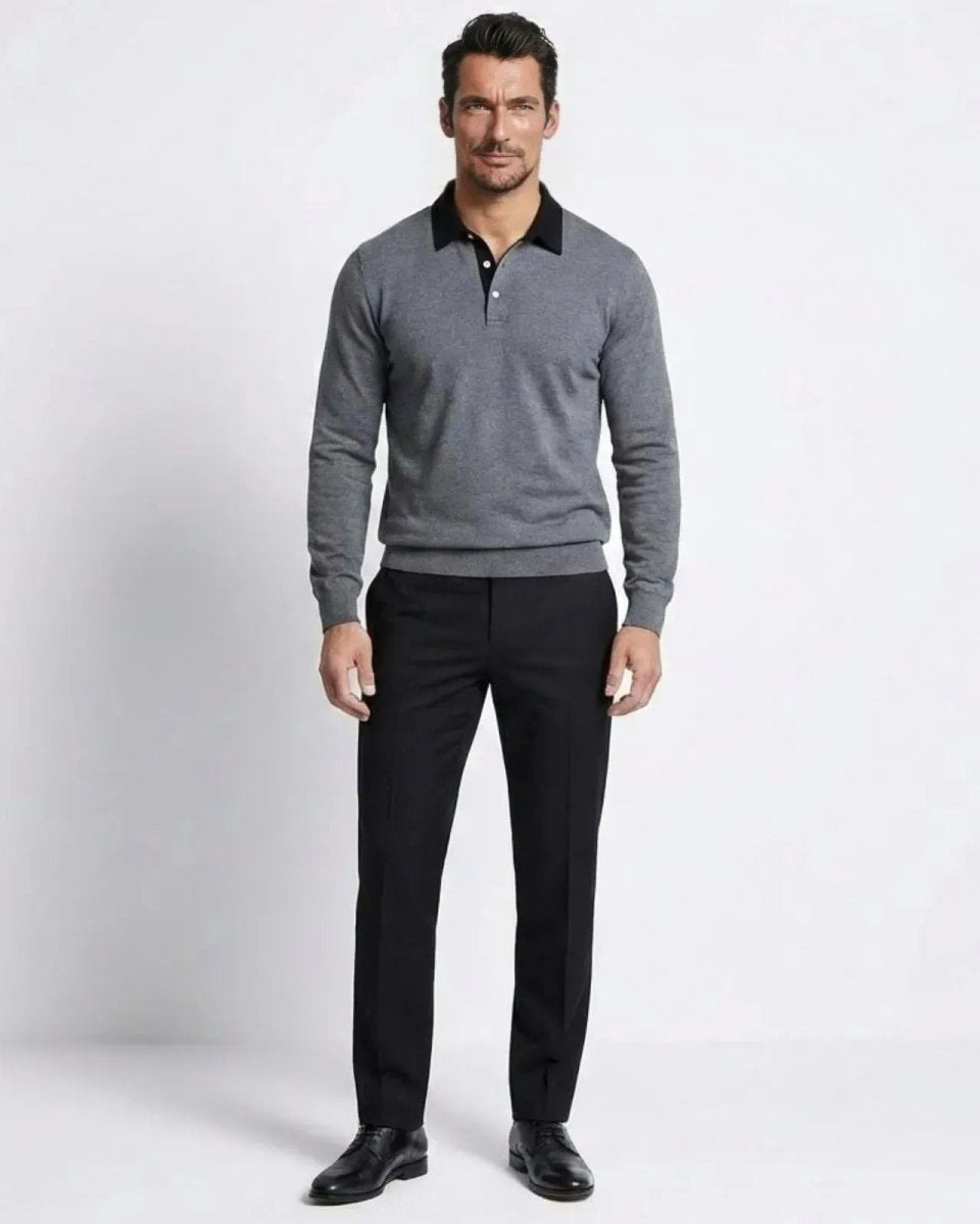 Model wearing the men's long-sleeve merino wool polo sweater in heather dark grey with a black contrast collar, styled with black trousers.