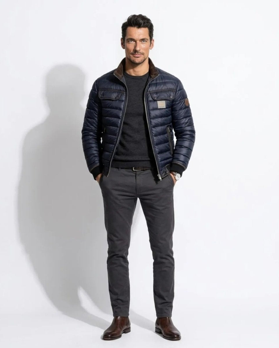 Front view of male model wearing the Fenlo Form navy blue quilted bomber jacket with smart casual grey trousers.