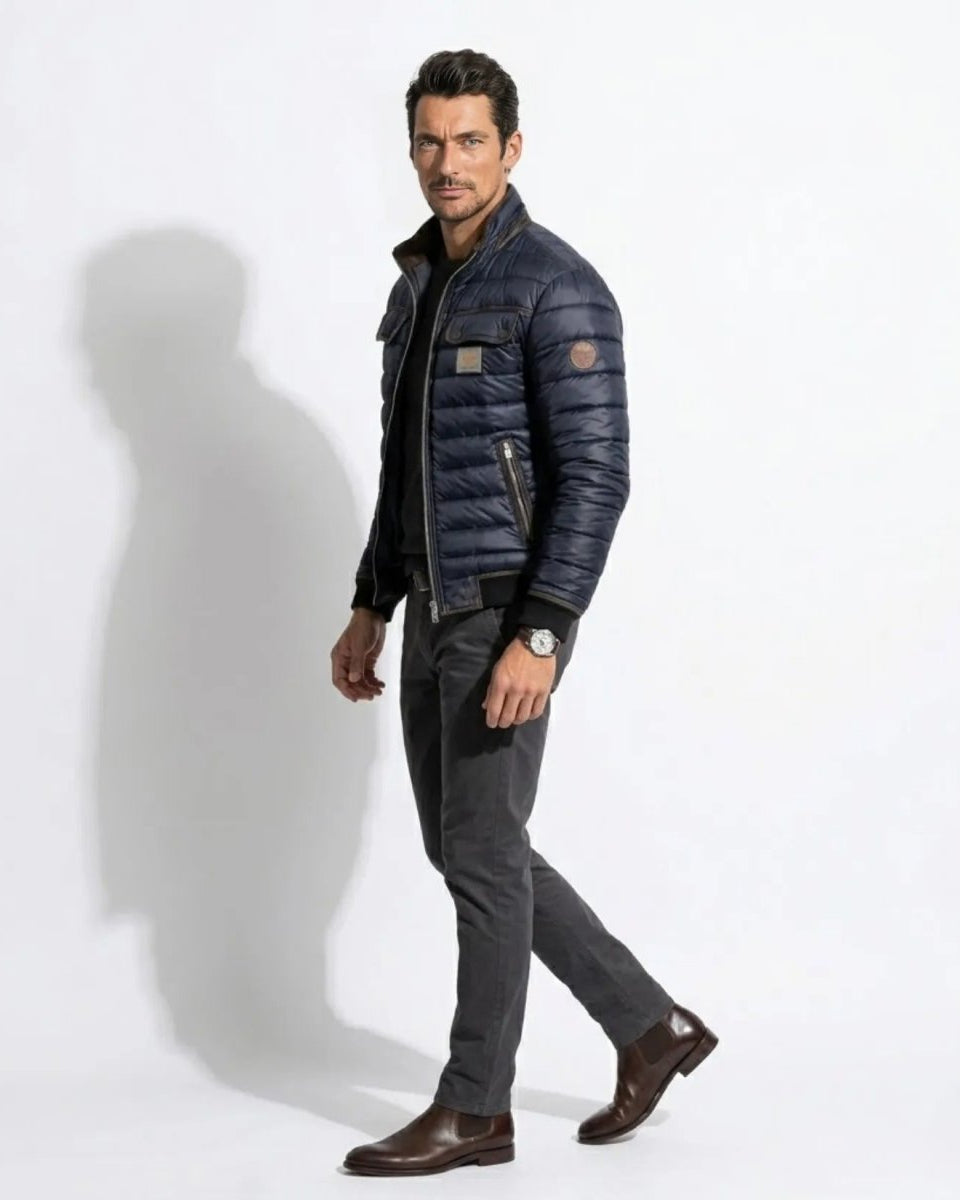 Side profile of male model walking in the Fenklo Form slim fit navy blue puffer coat highlighting the left arm logo patch.