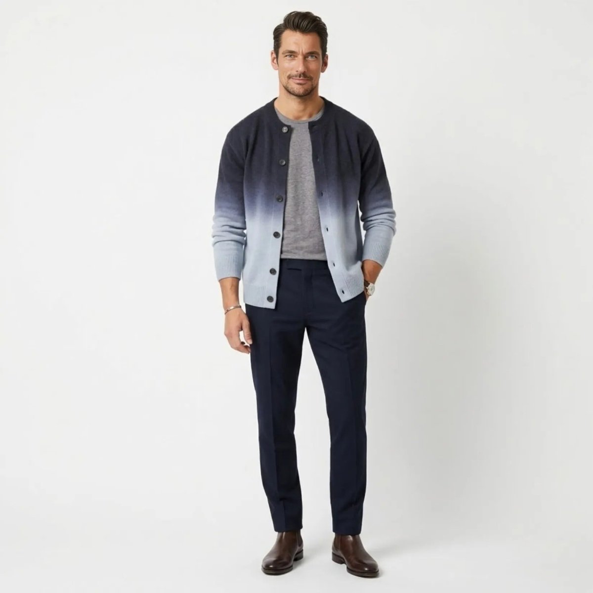 Male model wearing Kouvr luxury navy grey to light blue gradient Theodore knit cardigan over a grey tee with dark trousers.