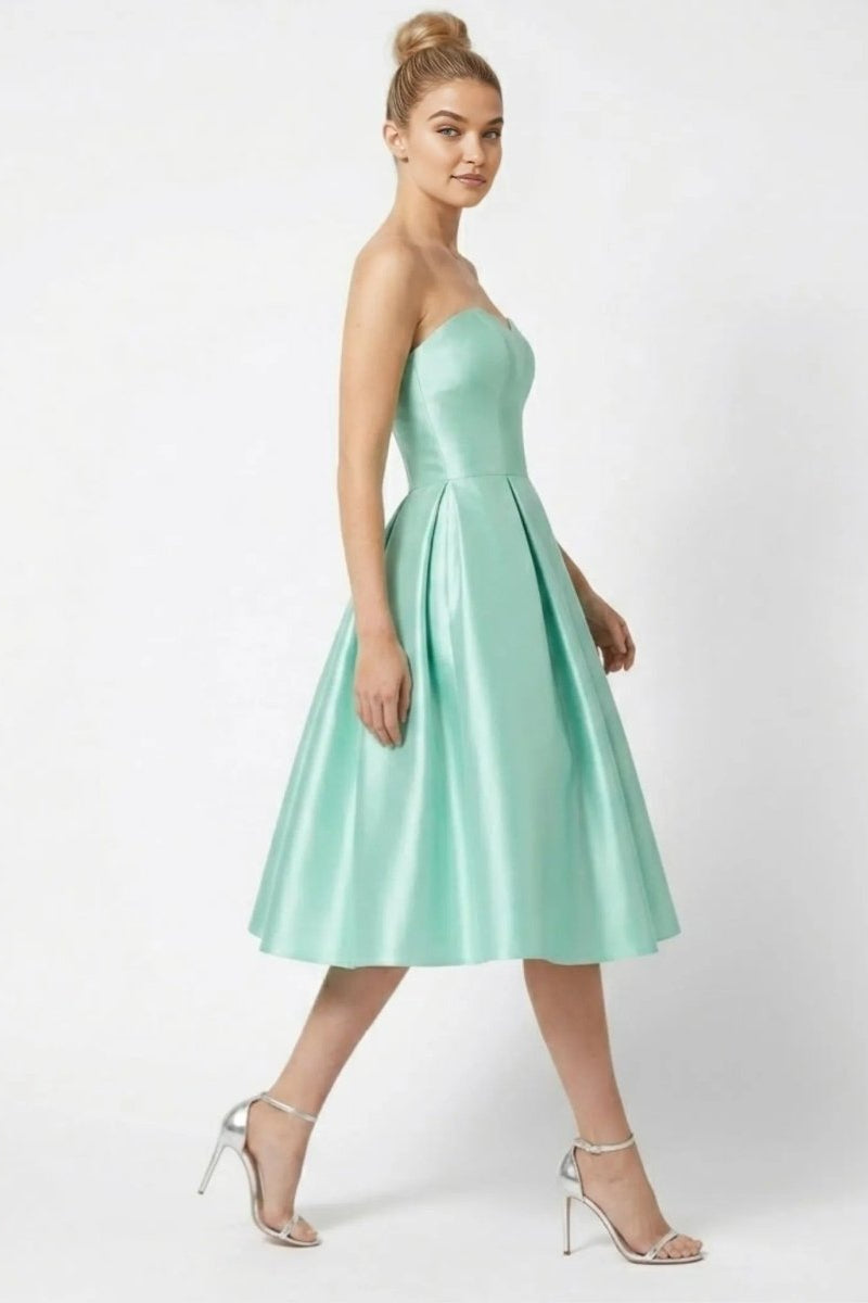 Side view of model walking in Fenlo Form mint green satin fit and flare pleated formal wedding guest dress