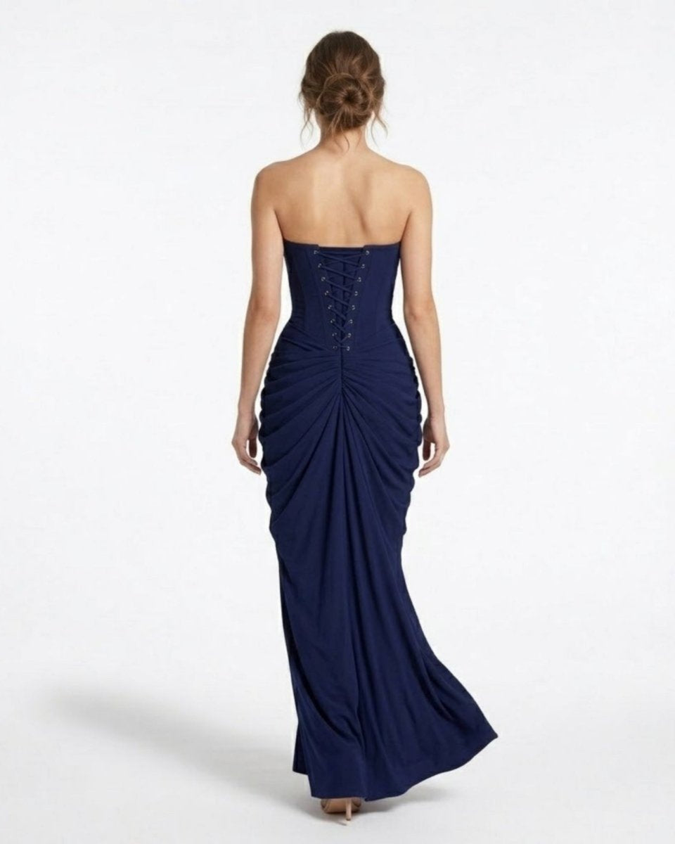 Back view of a navy blue formal maxi dress highlighting the adjustable lace-up corset back and elegant skirt drape.