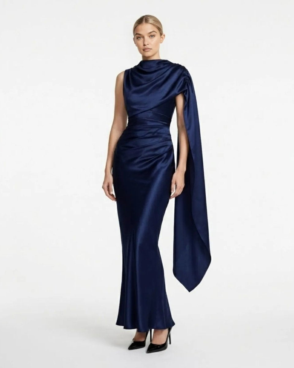 Front view of the navy blue satin asymmetrical evening gown with draped cape sleeve and ruched bodice.