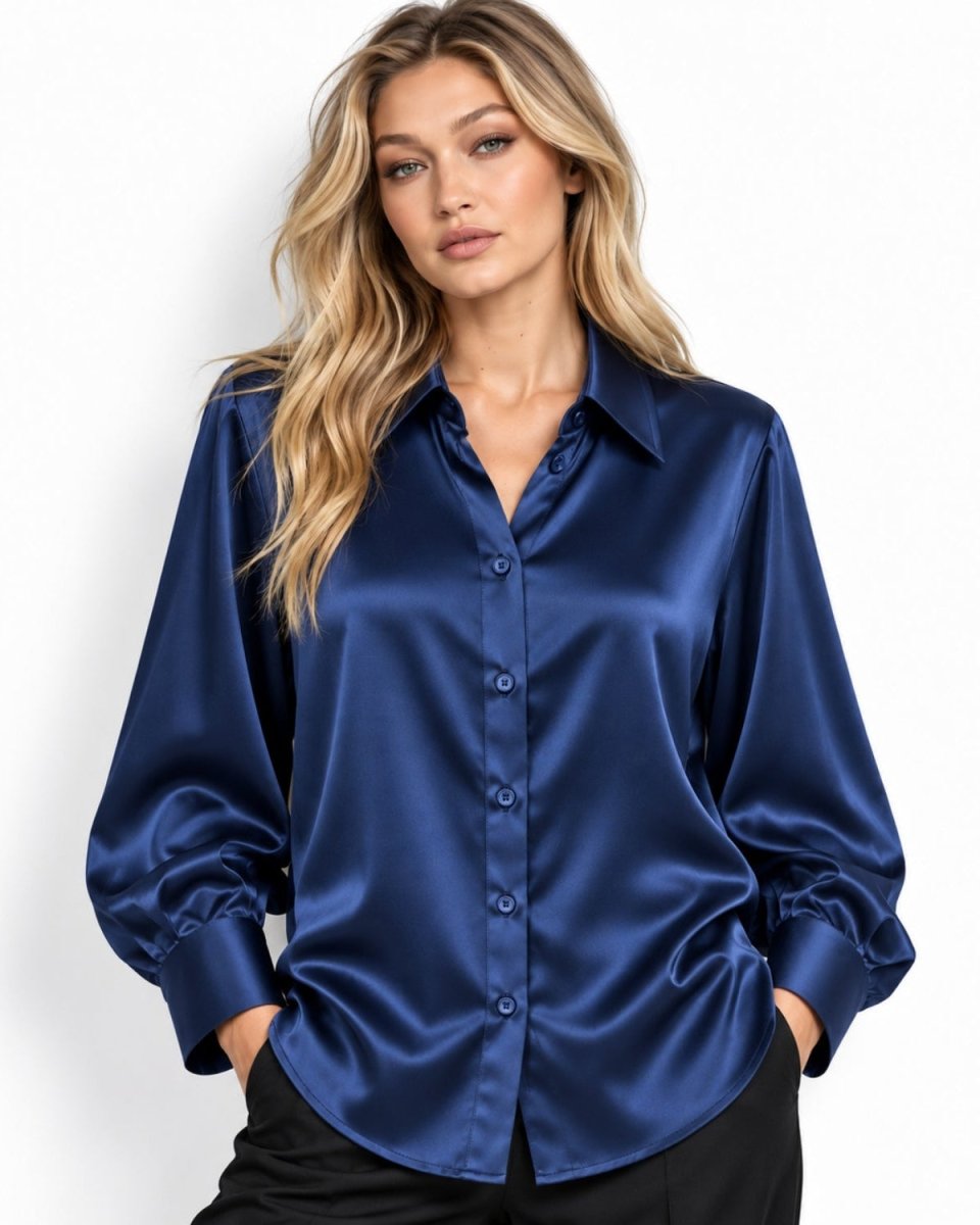 A woman modeling a long-sleeve mulberry silk button-up blouse in a rich navy blue color, paired with black pants, against a clean white studio background.