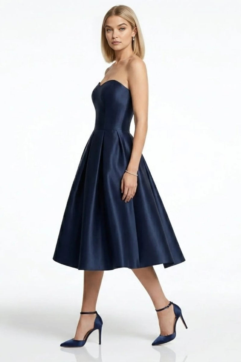 Woman wearing affordable luxury fit and flare dark blue cocktail dress side profile.