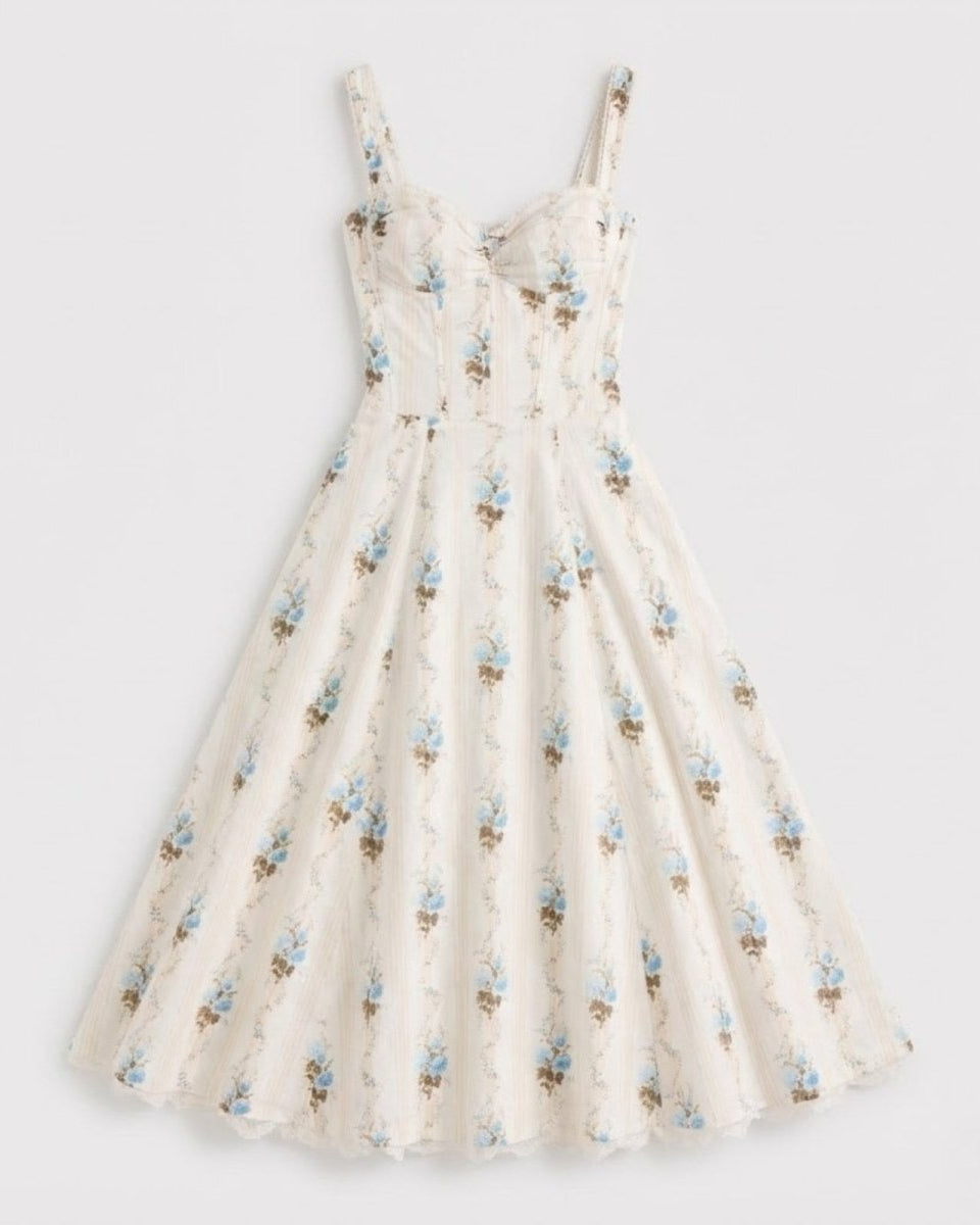 Flat lay of the Nefeli cream floral corset midi dress, highlighting the structured bodice, sweetheart neckline, and all-over blue floral and stripe pattern.