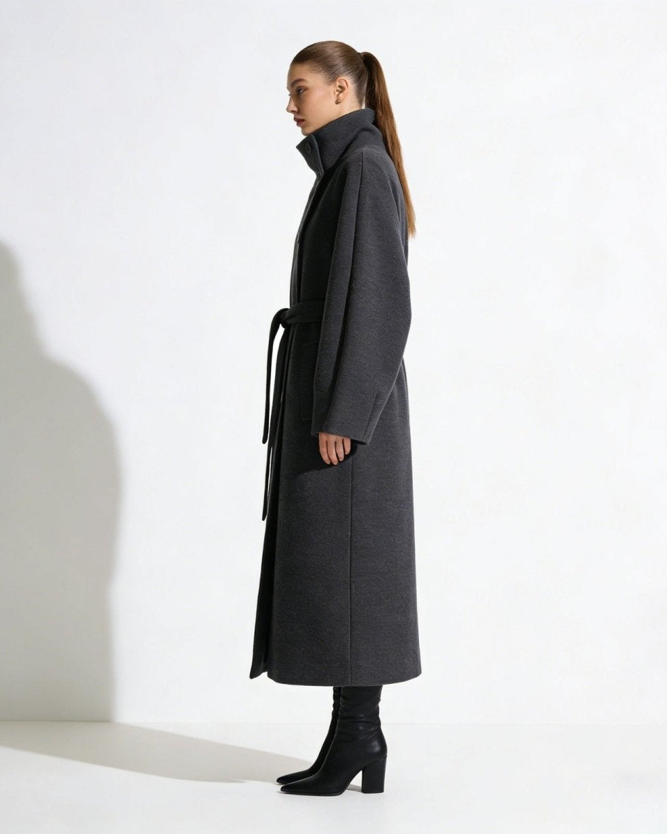 Side profile of a model in the oversized funnel neck wool coat in gray, highlighting the long silhouette and raglan sleeves.