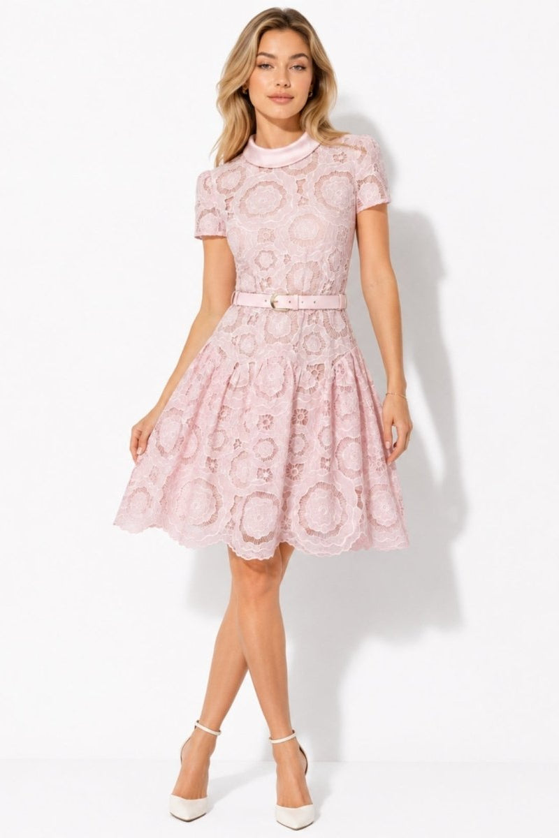 Woman wearing Fenlo Form pink floral guipure lace short sleeve mini dress with belt and satin collar facing forward.
