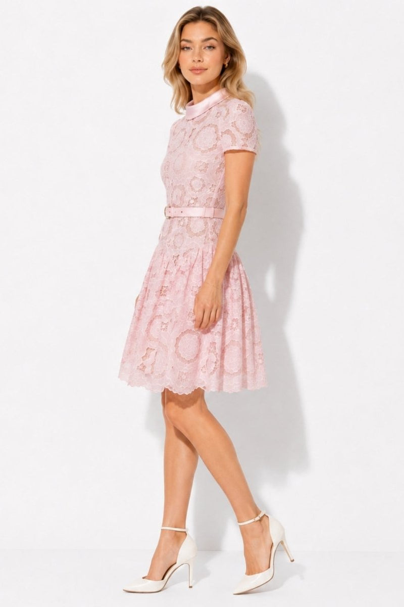 Side profile of woman in Fenlo Form pastel pink fit and flare lace party dress showing cinched belted waist.