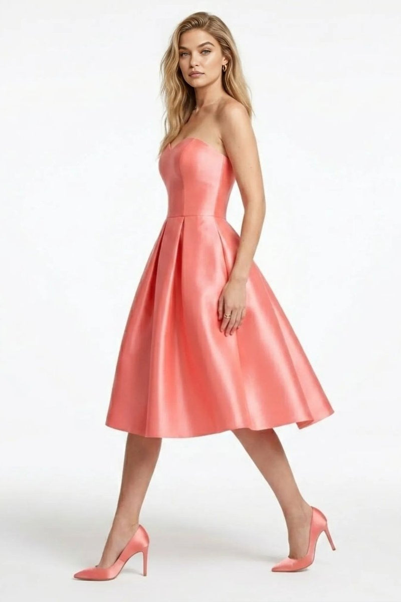 Side profile view of the pink pleated A-line satin cocktail dress highlighting the fitted strapless bodice.