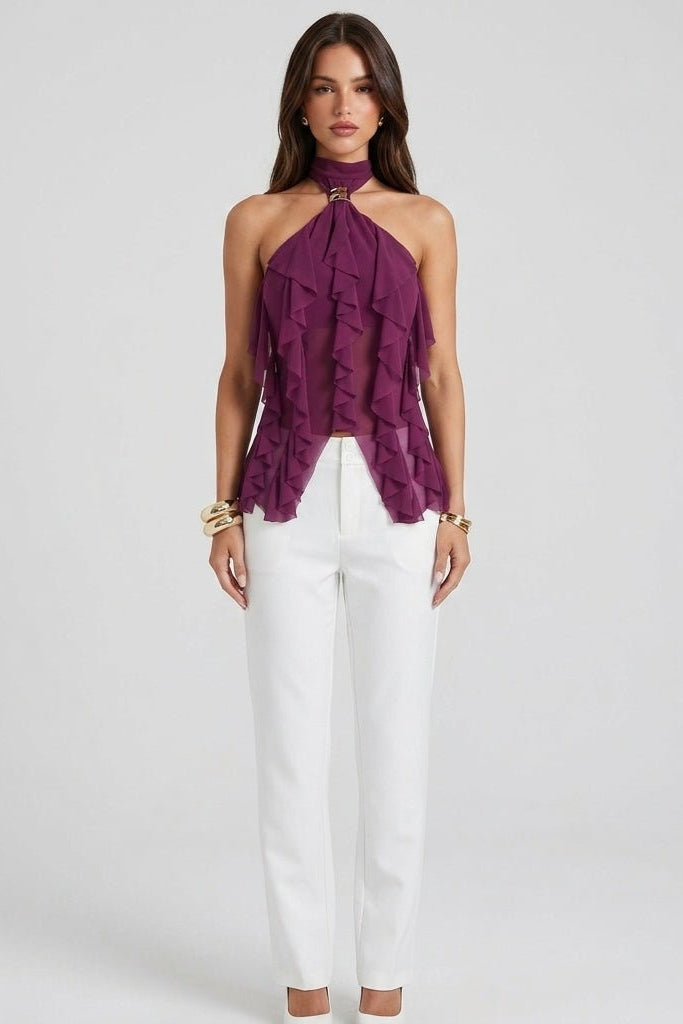 Full body studio shot of model in magenta sheer ruffle going out top paired with crisp white pants.