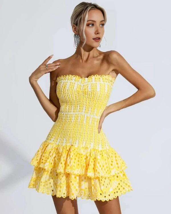 Woman wearing a yellow strapless dress with ruffled layers on a white background