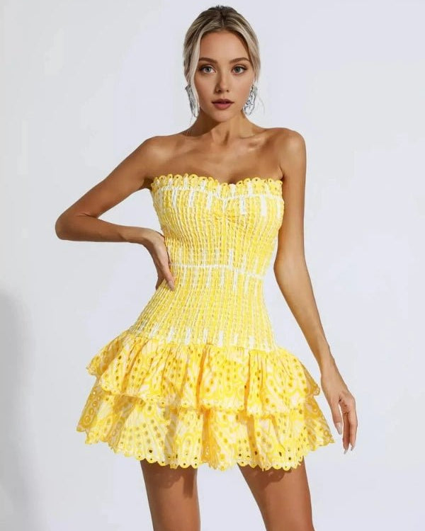 Woman wearing a yellow strapless dress with ruffled layers on a white background