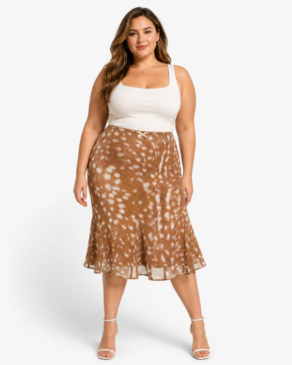 A woman modeling a brown and white tie-dye patterned midi skirt with a white ribbed tank top, standing against a light gray studio background.