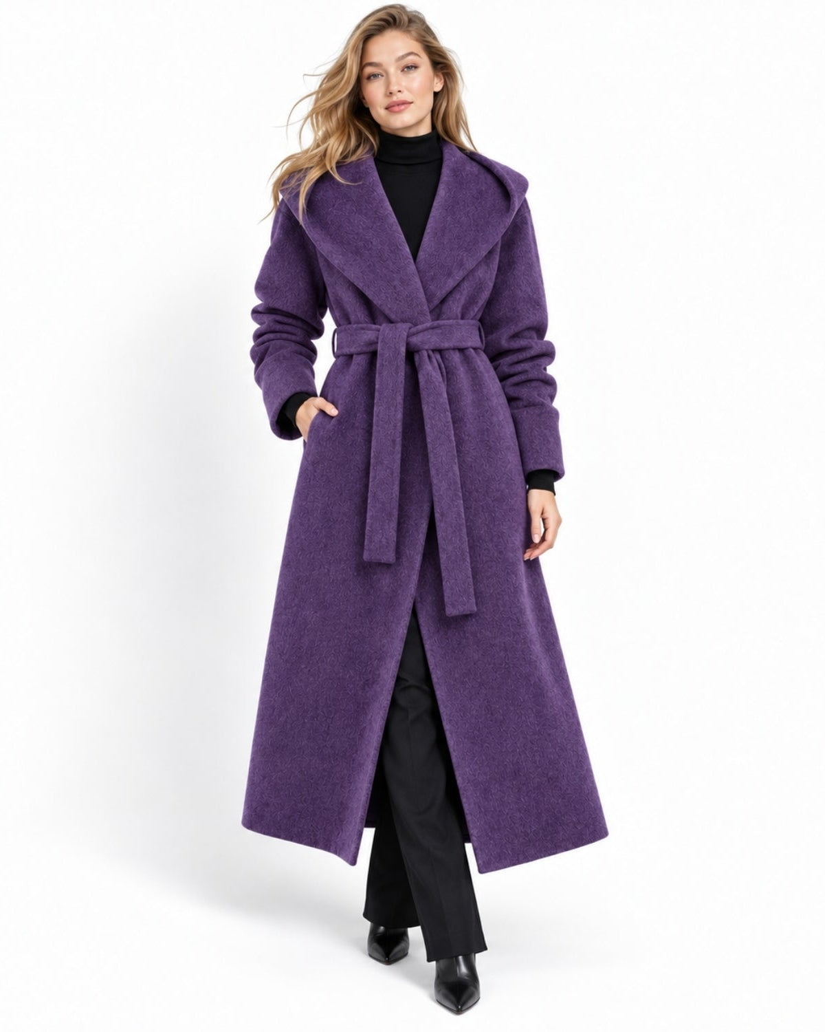 Front view of a woman wearing a luxury amethyst purple long wrap coat with an oversized hood and tie belt styled over black trousers.