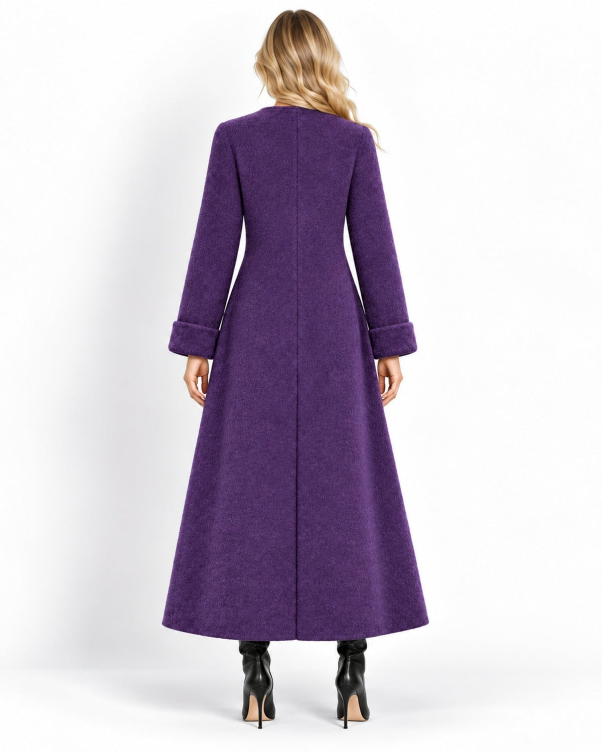 A woman viewed from the back wearing a long, wide purple coat with cuffed sleeves and black high-heeled boots against a plain white studio background.