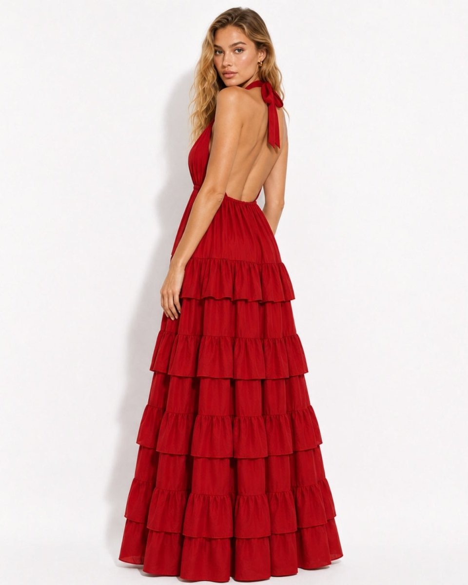 Side angle of a woman in a red backless halter maxi dress, showcasing the open back design and flowing tiered ruffles.