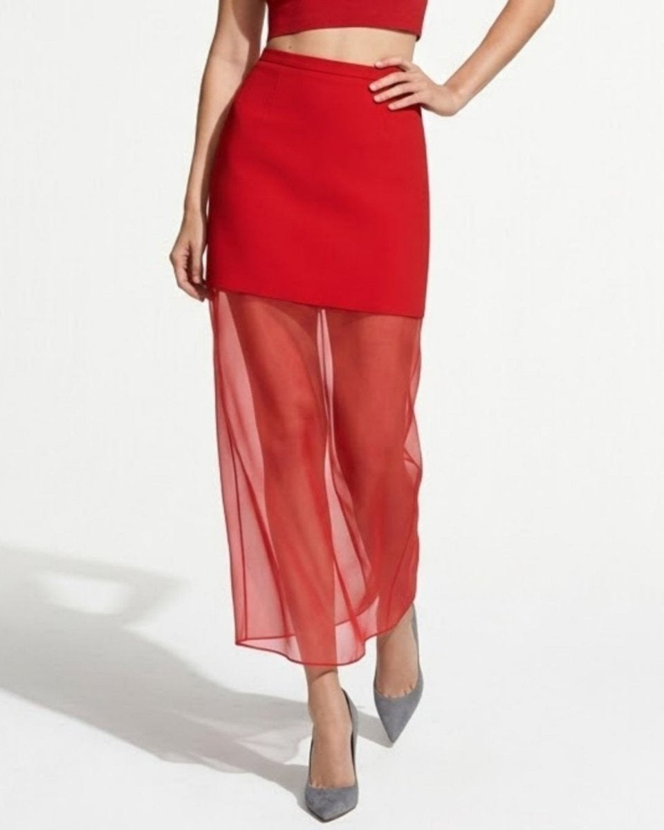 Model walking wearing red high waisted mini skirt with sheer maxi overlay and matching crop top.
