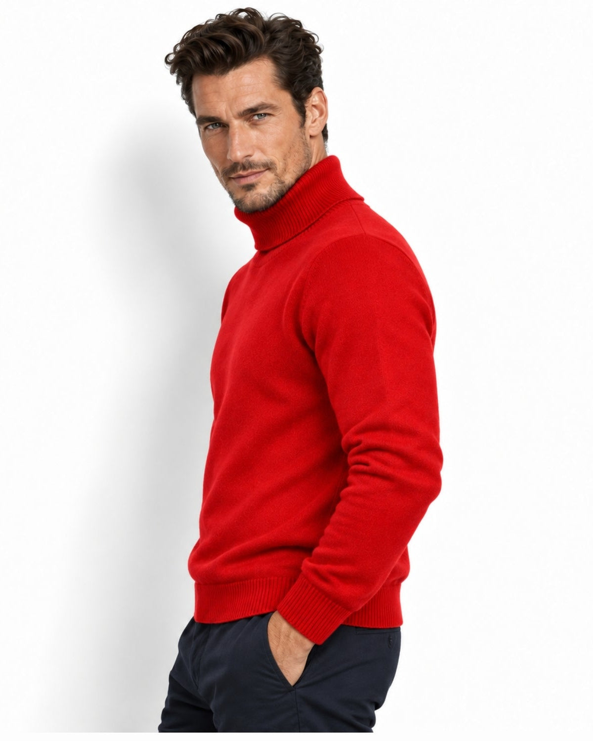 A man wearing a bright red knit turtleneck sweater and dark navy trousers, photographed against a clean white studio background.