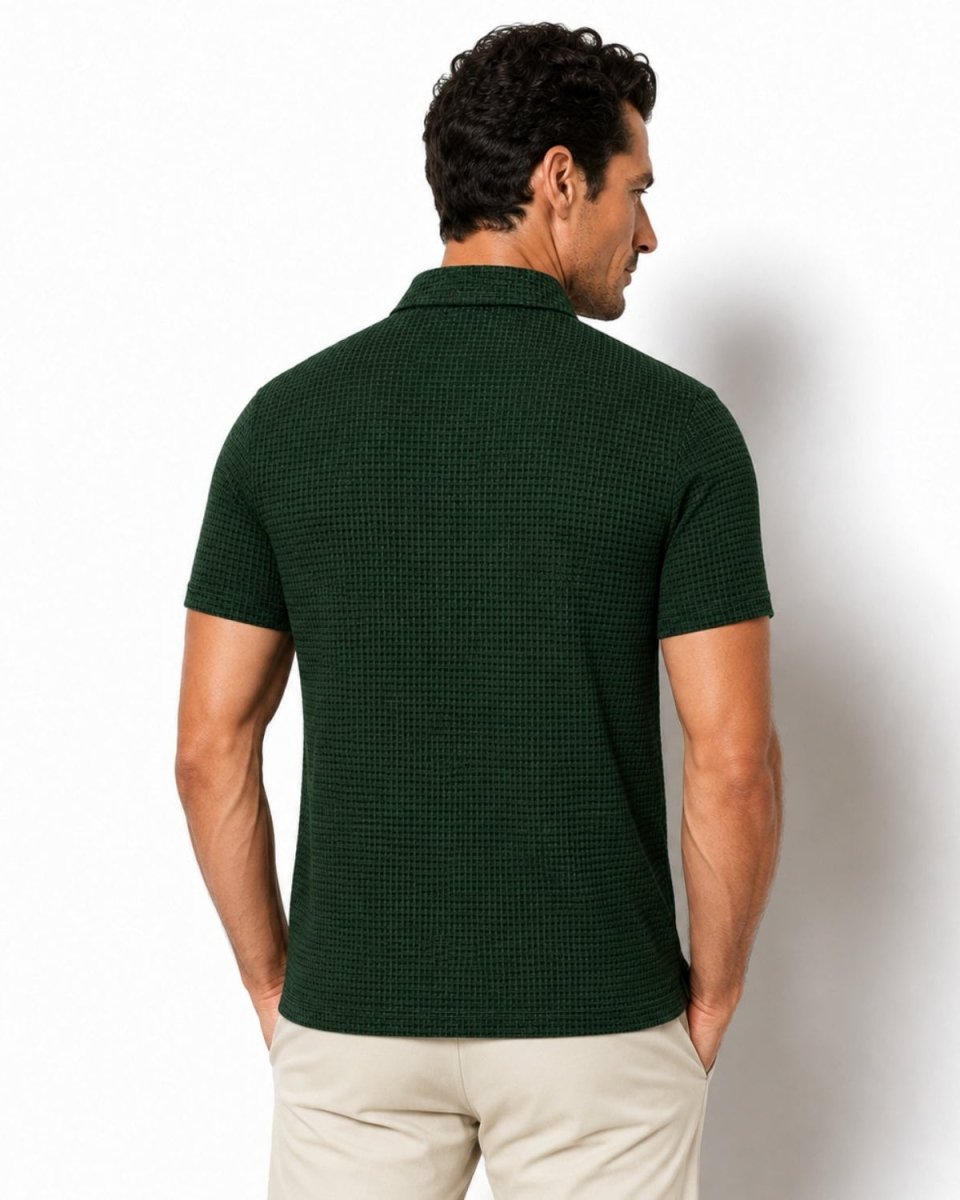 A man shown from the back wearing a dark green short-sleeve polo shirt with a textured waffle pattern and light beige trousers, set against a plain white studio background.