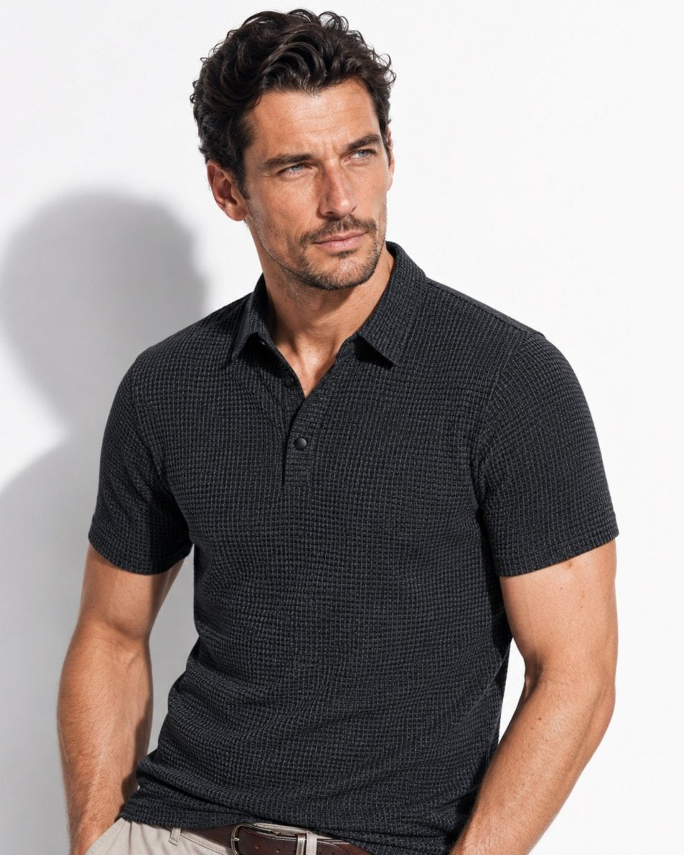 Man wearing a black patterned polo shirt against a white background