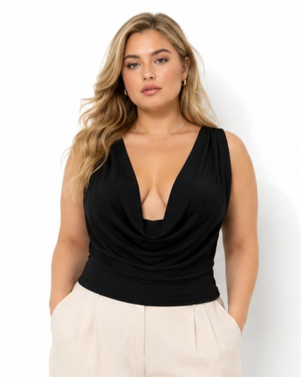A woman modeling a black sleeveless cowl-neck top with a deep V-neckline, paired with light beige trousers, against a plain white studio background.