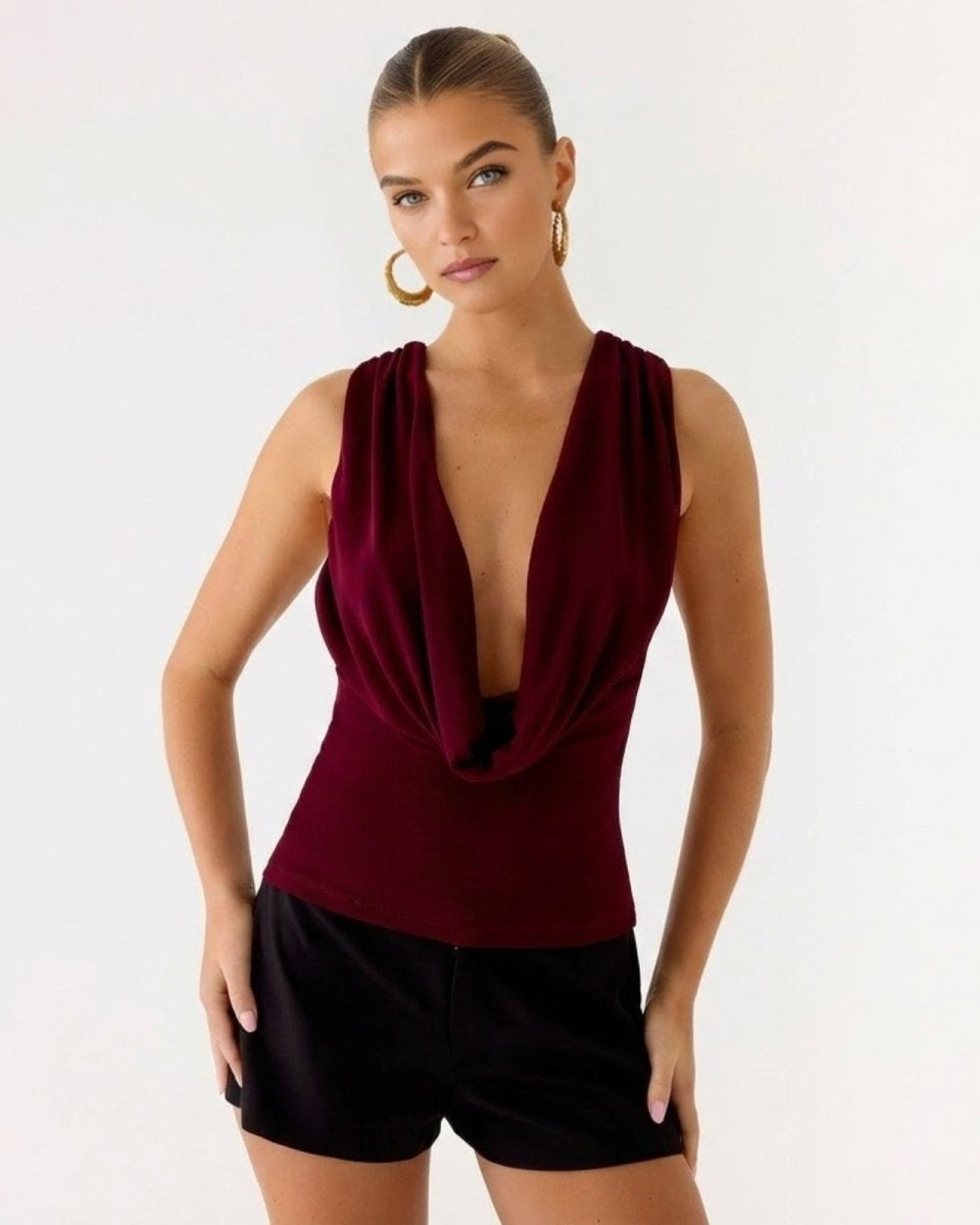 Model wearing the Rhea top in burgundy, showcasing the deep draped cowl neckline.