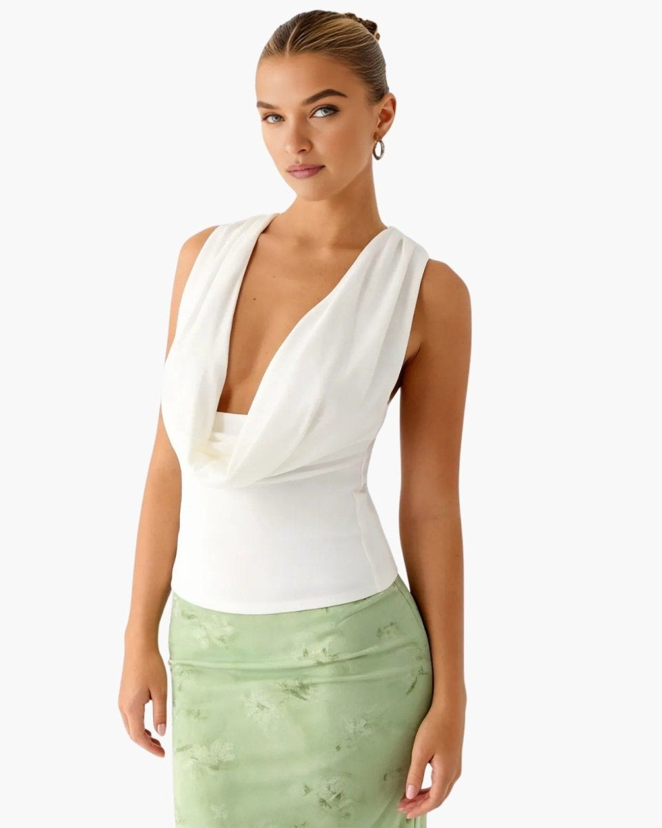 A three-quarter view of a woman wearing a white draped v-neck top with her hair in a bun, showcasing the top's fitted silhouette.