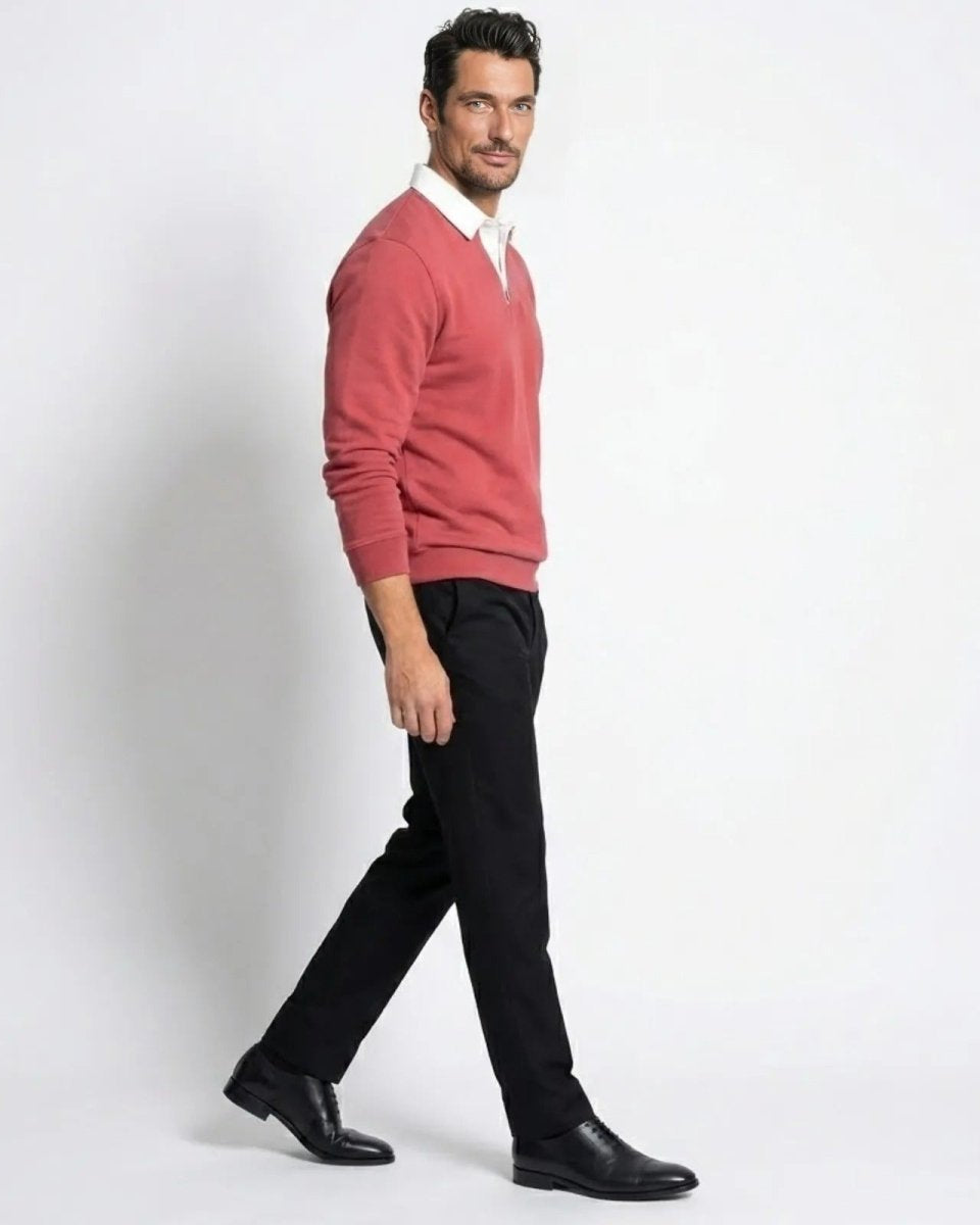 Side profile of a model walking in the Rhodes rosewood red polo sweater and black trousers.