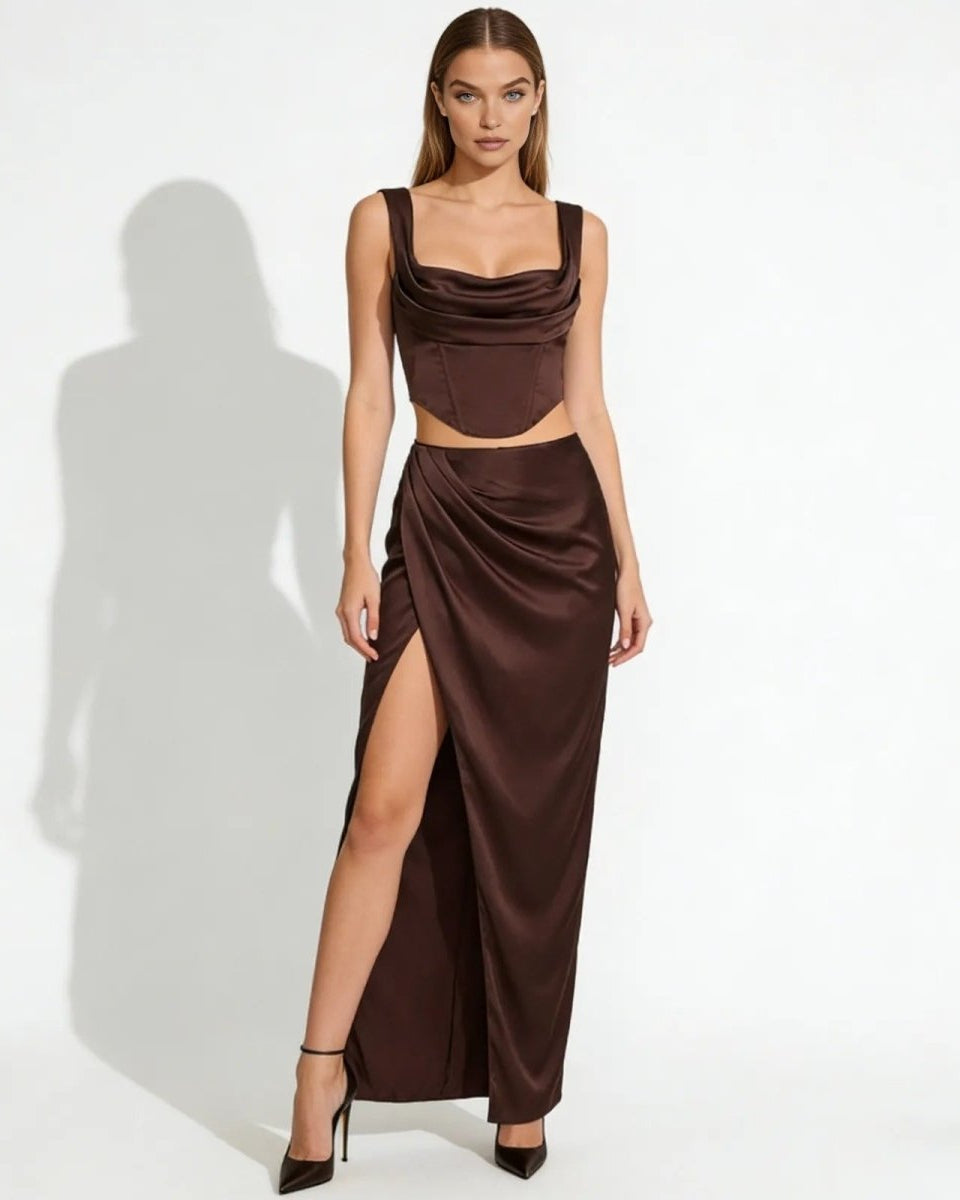Model wearing the Rona dark brown satin set, showing the cowl neck corset top and high-slit draped maxi skirt from the front on a white background.