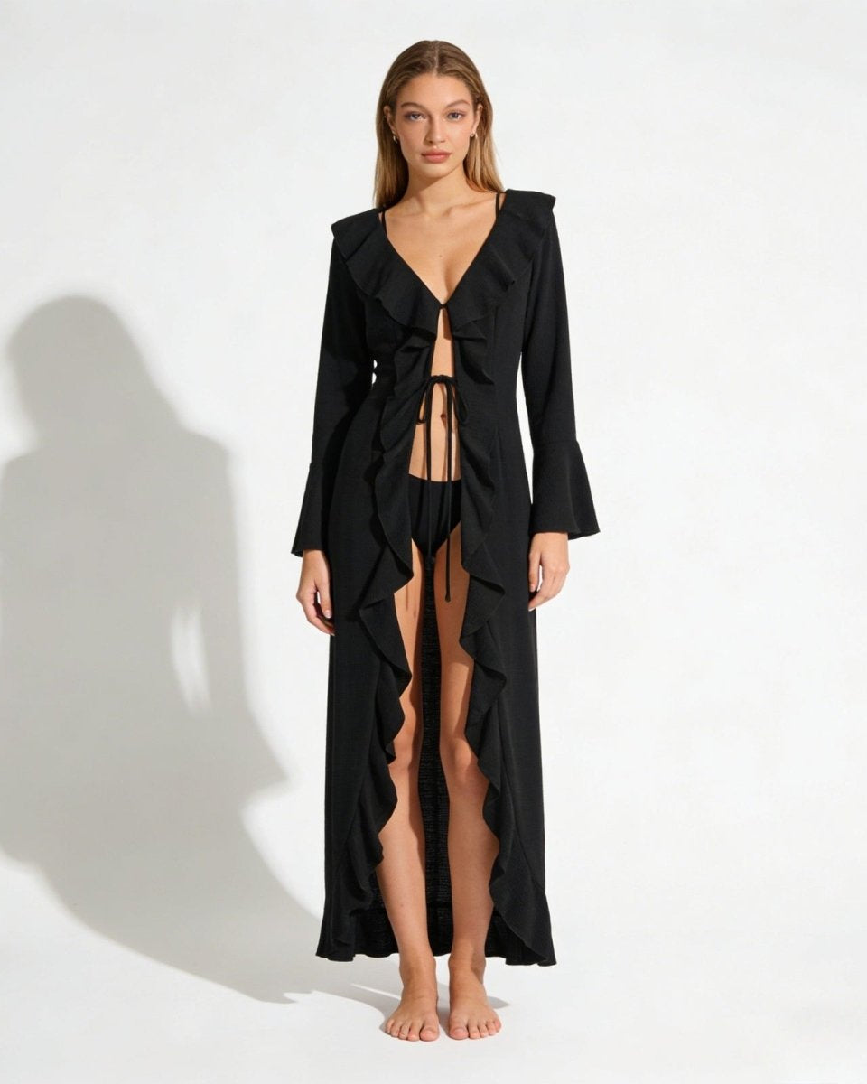 Model wearing the Roseta black ruffle maxi cover-up, showing the V-neck, tie-front detail, and full-length ruffle trim.
