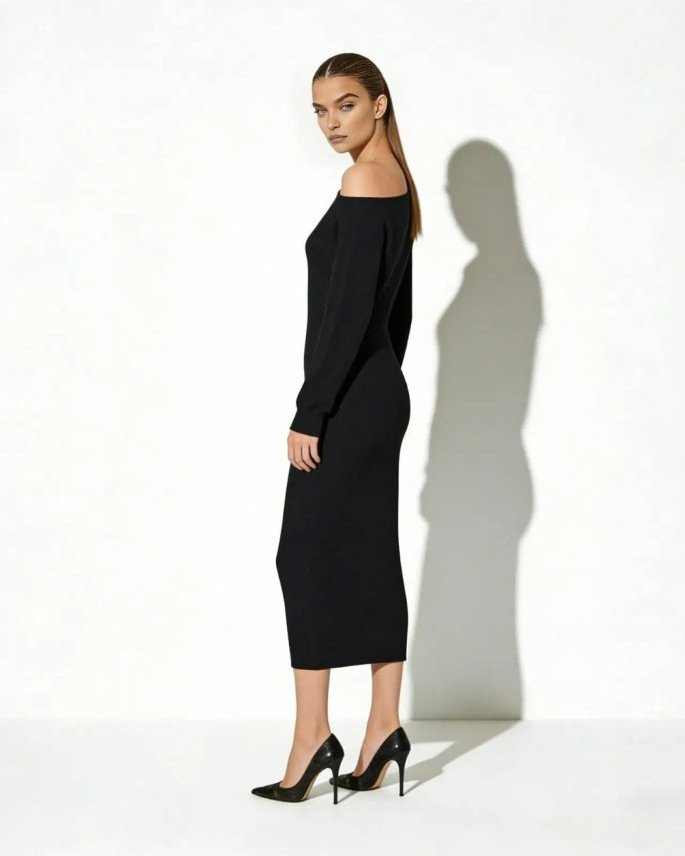 Side profile of a woman in a long-sleeve asymmetrical black sweater dress showing its bodycon silhouette.