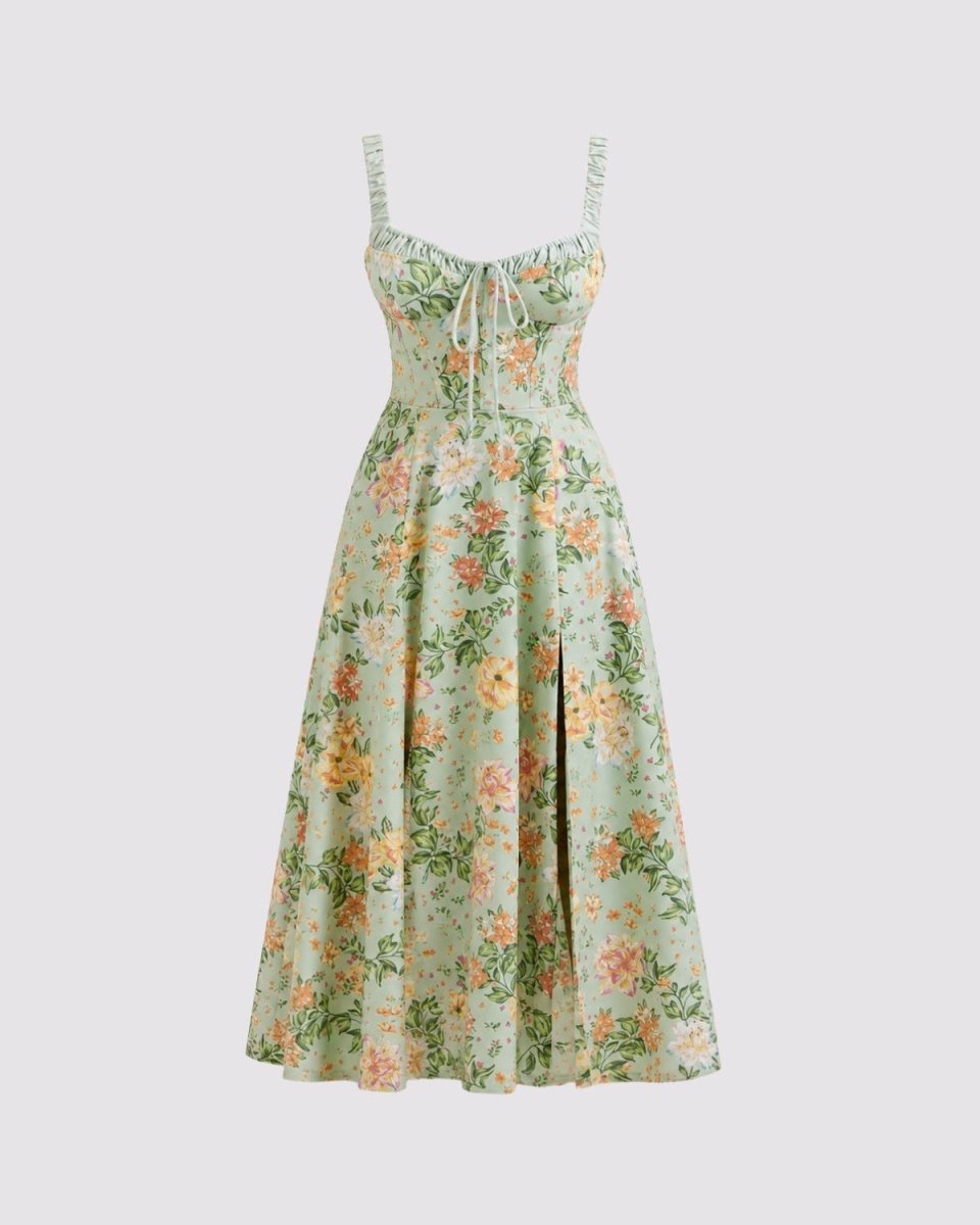 A sleeveless midi dress with thin shoulder straps, a sweetheart neckline, and a corset-style bodice, featuring a green base with a yellow and orange floral print. The dress is shown against a solid light gray background.