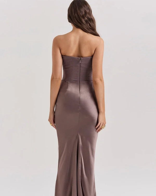 Woman wearing a strapless brown evening gown on a plain background