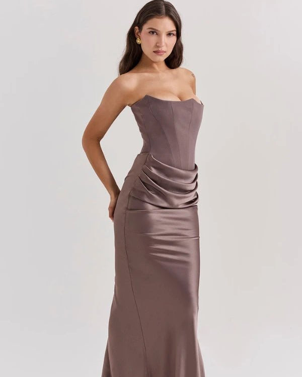 Woman wearing a strapless, floor-length dress with a draped design on a white background