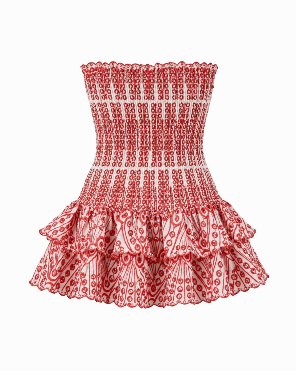A strapless smocked mini dress with a red and white geometric pattern, featuring a fitted bodice and a tiered ruffled skirt, shown against a plain white background.