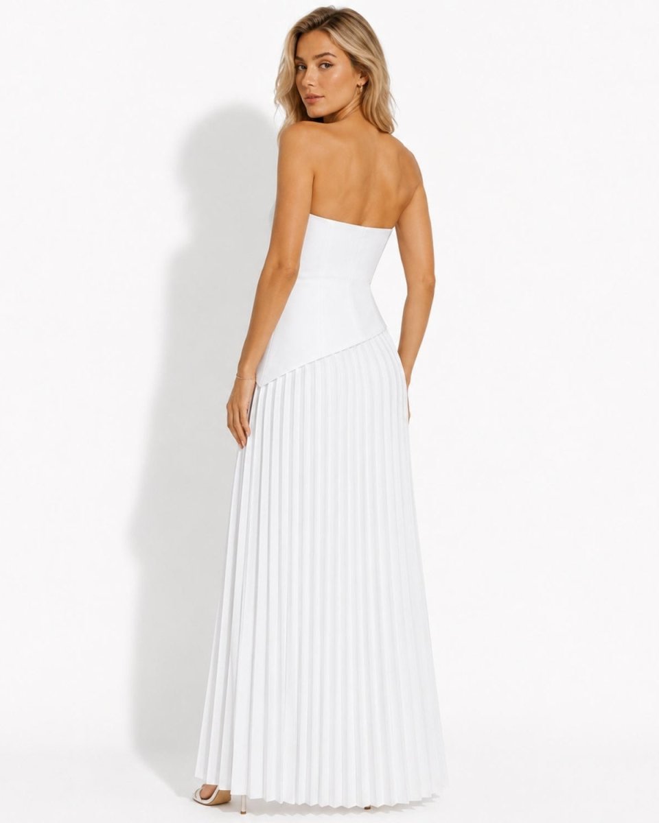 A woman modeling a strapless white maxi dress with a structured corset-style bodice and a long pleated skirt, shown from the back against a plain white studio background.