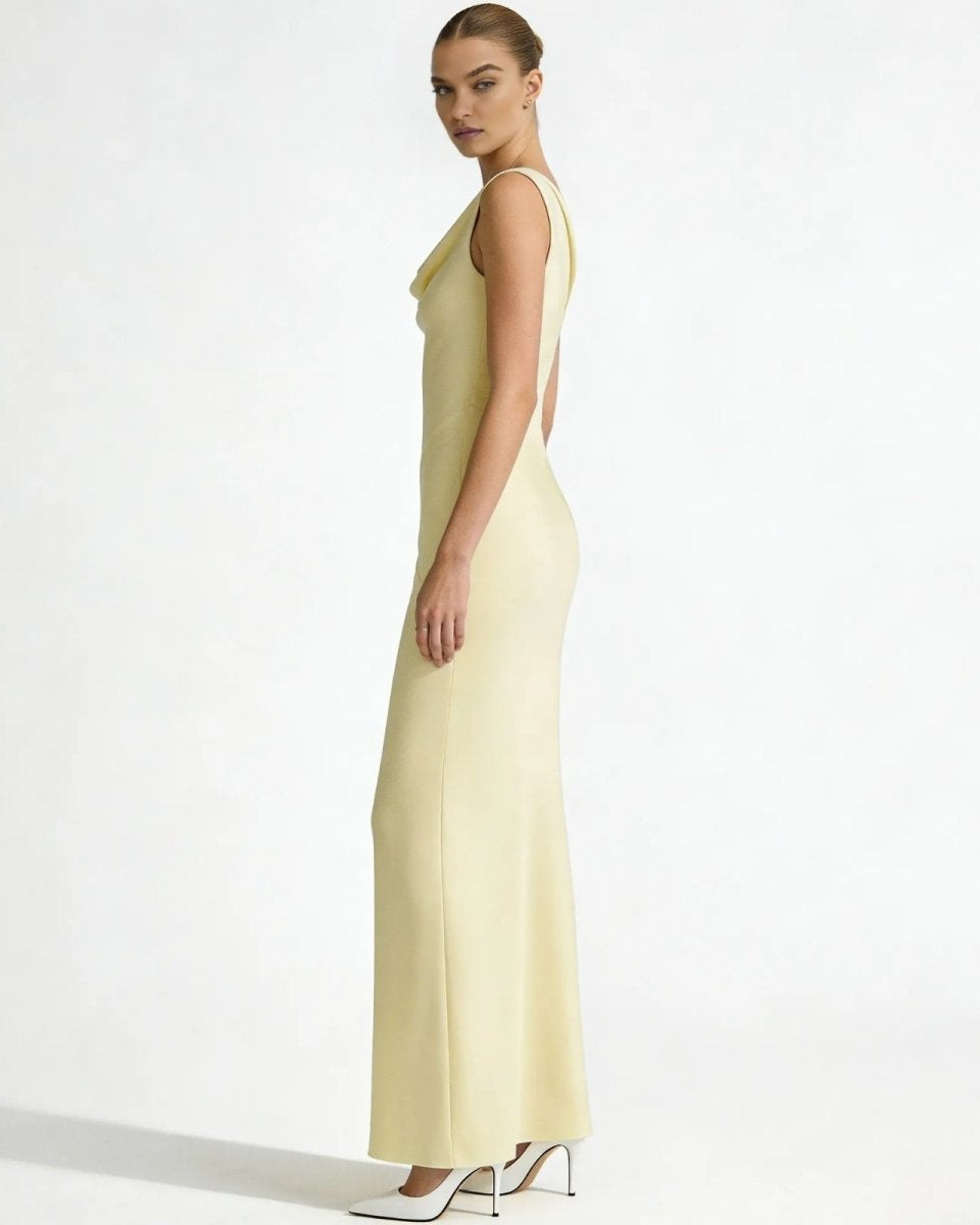 Side profile of a model in the Vickie Gown, showcasing the elegant column silhouette and draped cowl neckline of the pale ivory dress.