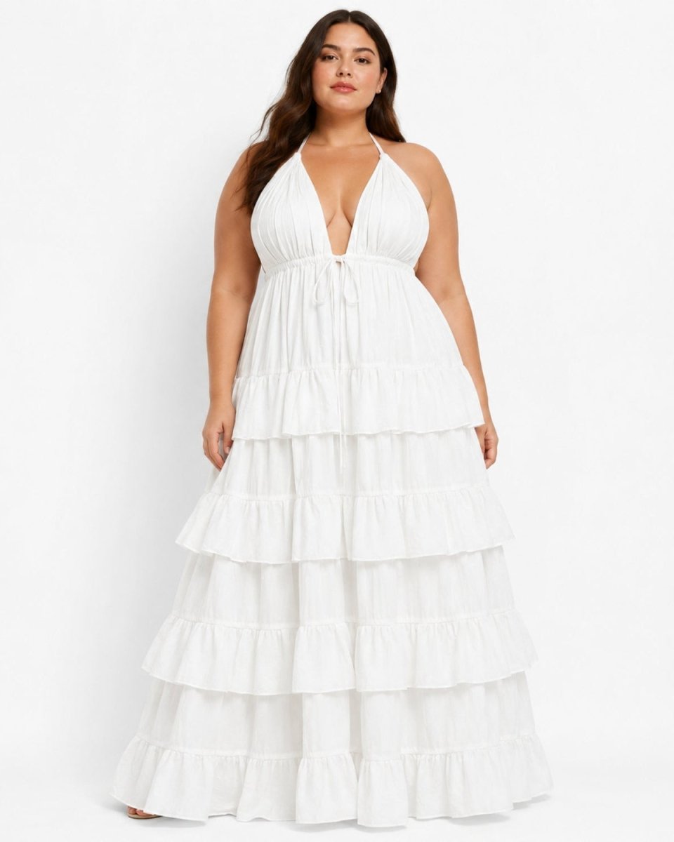 A plus-size woman modeling a white halter-neck maxi dress with a tiered ruffle skirt against a plain white studio background.