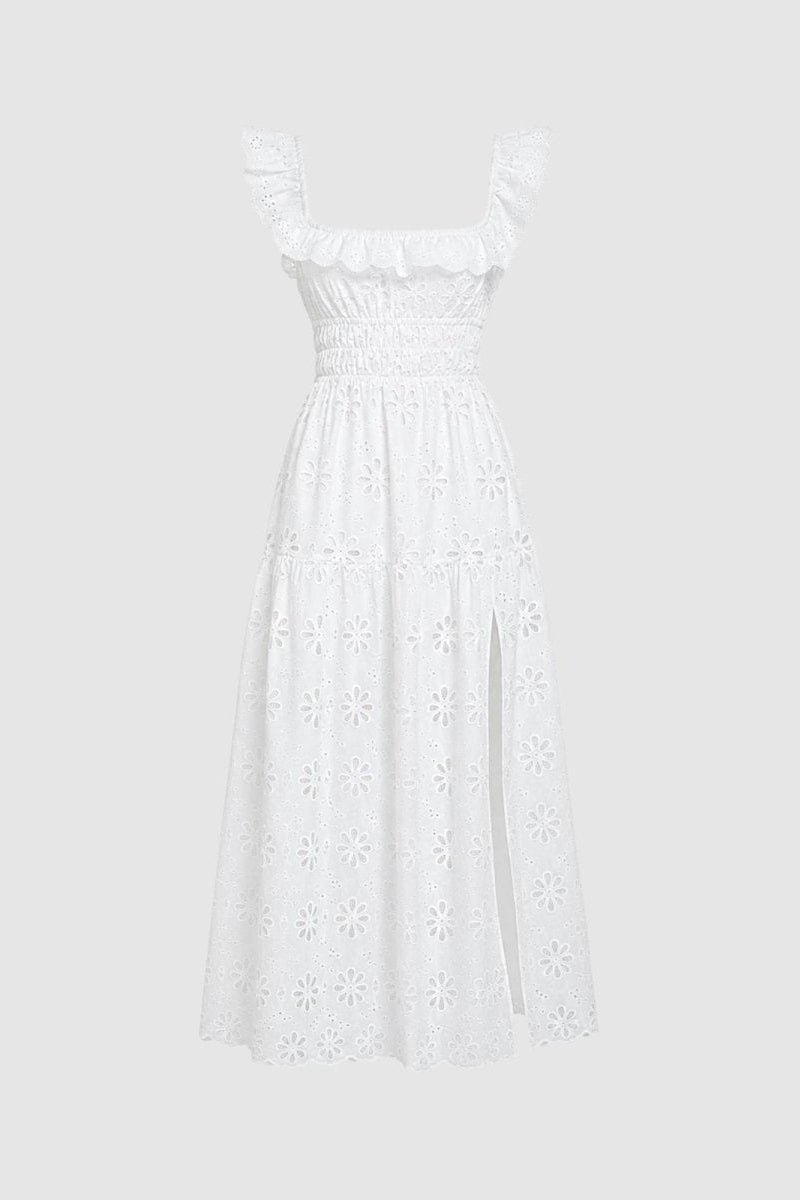 Studio shot of white smocked eyelet maxi dress with ruffled straps and side slit on a light grey background.