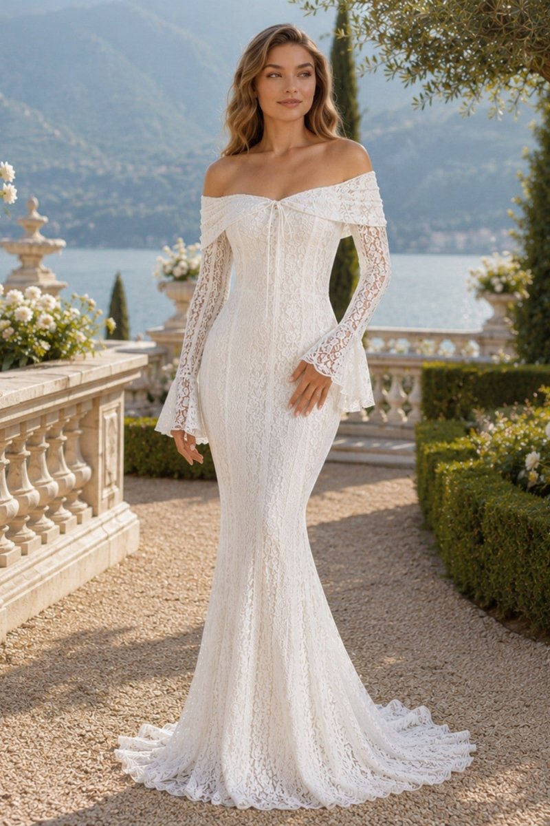 An off-the-shoulder lace wedding gown with long flared sleeves and a fitted mermaid silhouette, worn by a model standing on a stone terrace with a lake and mountains in the background.