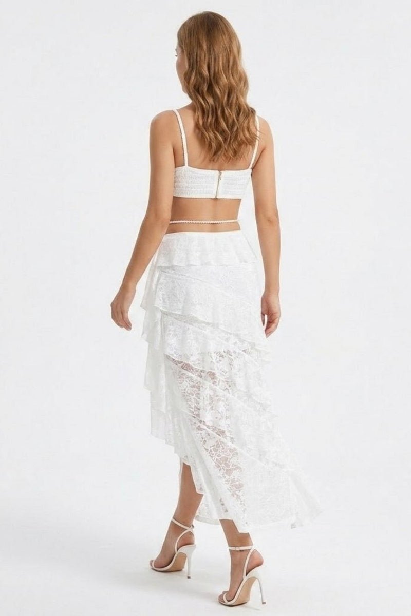Woman wearing a white lace skirt and top on a plain background